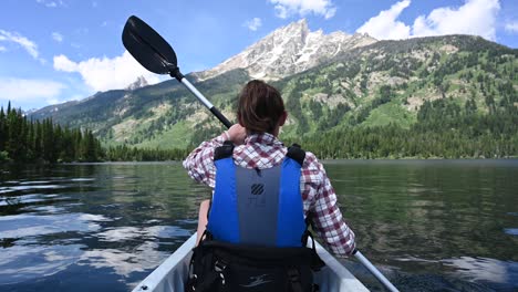 woman kayaks in below the grand tetons