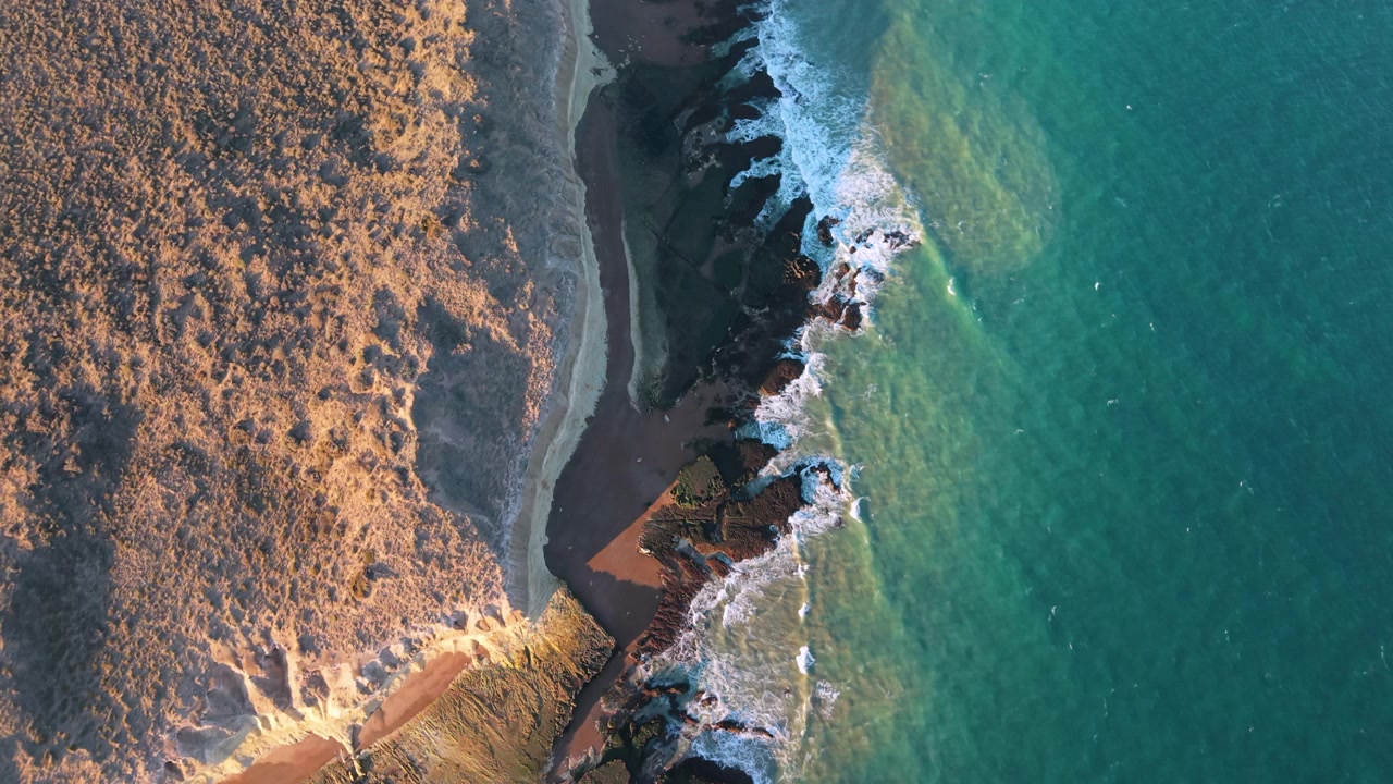 Una splendida vista dall'alto di onde che si infrangono lungo la costa frastagliata di Puerto Madryn