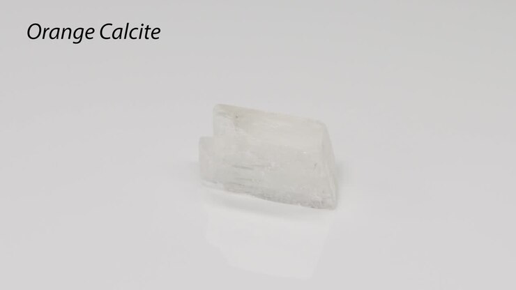 Orange Calcite crystal rotating on white background