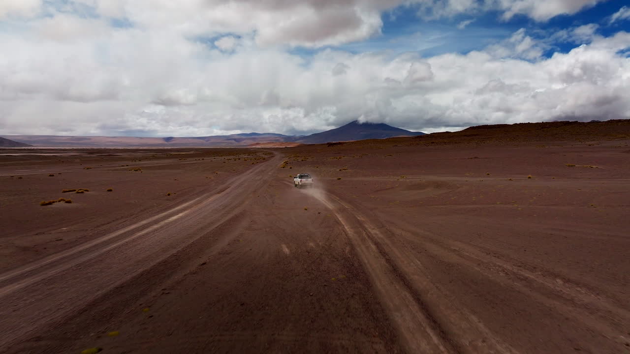 Utility truck drive on dusty dirt road through Siloli desert in Bolivia. Aerial