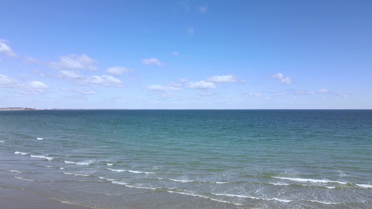 몇 개의 작은 구름이 있는 맑고 푸른 하늘 아래 아름다운 바다와 수평선의 정적인 무인기 전망