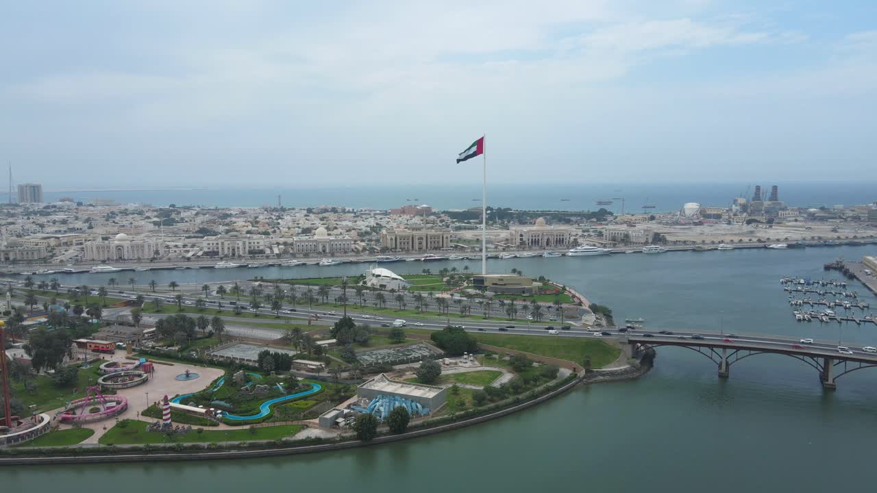 bandera de los emiratos árabes unidos: vista superior de la bandera de los emiratos árabes unidos ondeando en el aire sobre la isla de la bandera de sharjah, ciudad de sharjah, día nacional de los emiratos árabes unidos, video de 4k
