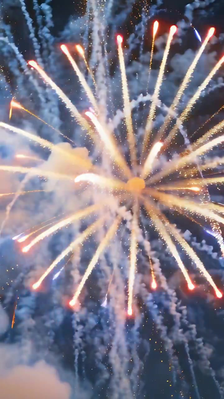 Vertikales Video: Berstende Feuerwerkskörper senden goldene Funken über den Nachthimmel für ein Festival, ein Komet steigt auf