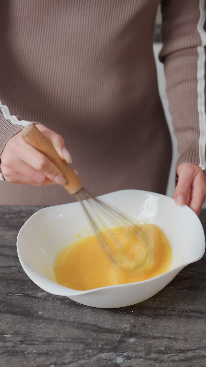 primer plano de manos golpeando huevos en un cuenco blanco en la encimera de la cocina, con un observador cerca, la escena de la cocina captura la preparación de alimentos, el trabajo en equipo y la cocina en el hogar en un ambiente doméstico cálido