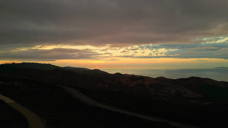 Toma-Panorámica-Aérea-Con-Drones-De-Un-Gran-Molino-De-Viento-Trabajando-En-Terreno-Montañoso-Al-Atardecer