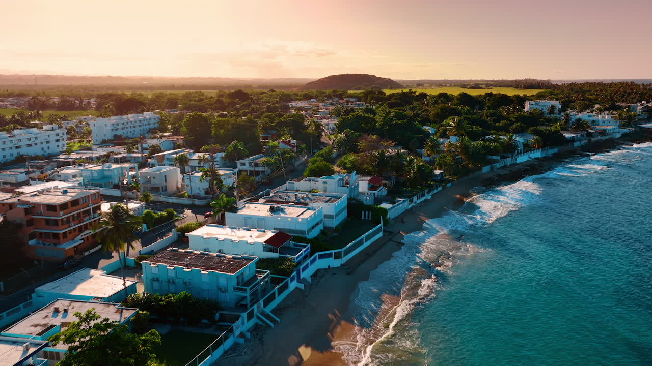 Imagens ao longo da praia arenosa com vilas localizadas perto da costa. Cenário natural verde iluminado pelo sol poente ao fundo. Porto Rico.