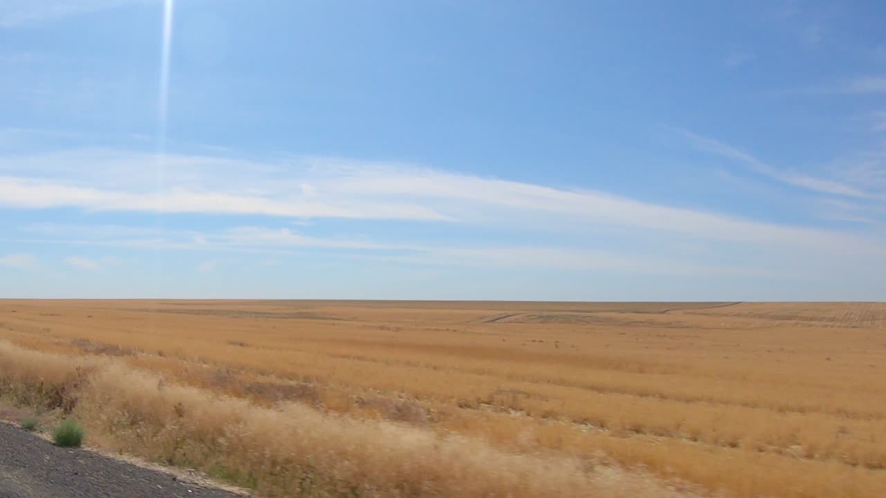pov por la ventana del pasajero mientras conduce por un campo de trigo cosechado recientemente en el área agrícola de las tierras altas de okanogan del estado central norte de washington