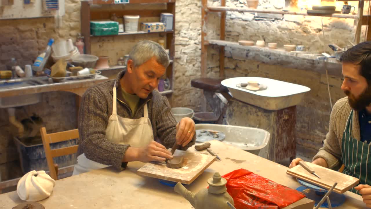 Potter teaching his colleague to mold the clay