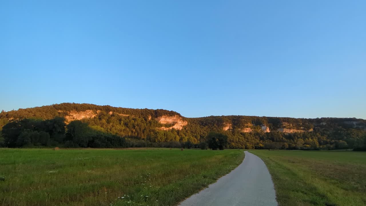 pan a través de la campiña francesa al atardecer con un largo camino sinuoso y campos vacíos cosechados