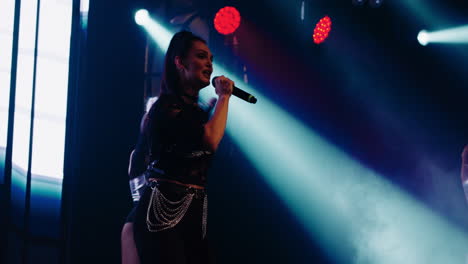 a female singer performing on stage with backup dancers