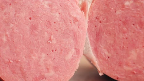 ham italian mordatella, man slices of traditional italian antipasti mortadella sausage on a wooden cutting board, close up macro of chicken or turkey jamon, fat breakfast dish.
