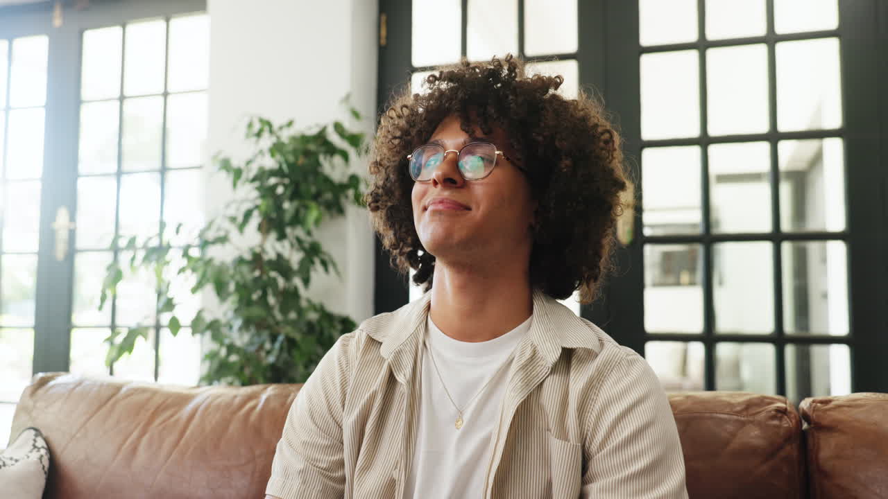 Young Man Meditating and Opening Eyes on Couch