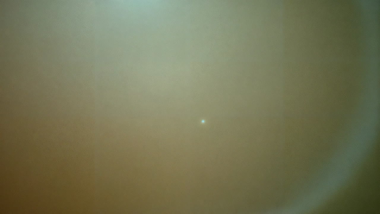 Abstract image of a bright white dot on a blurry yellowish background
