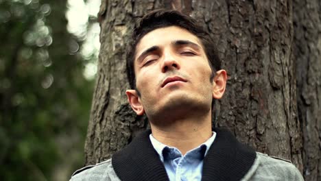 Hopefull-Man-Leaning-Against-Tree-At-Park