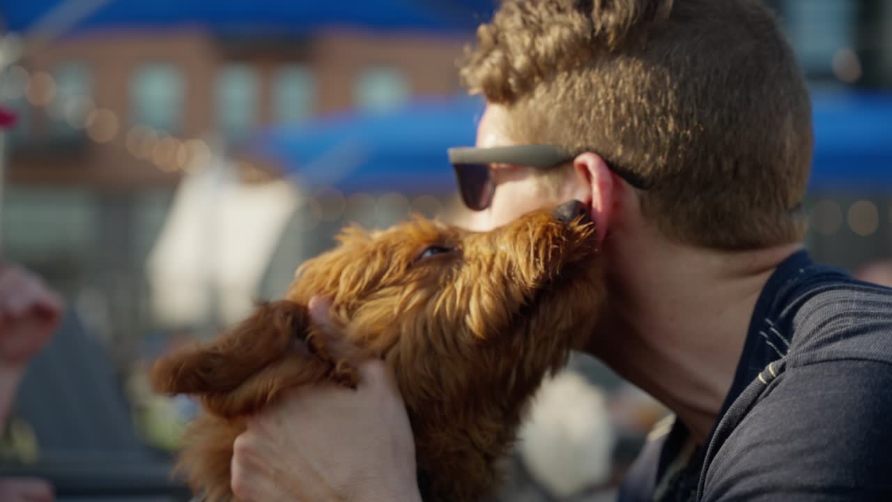 A puppy licks a young man in the face