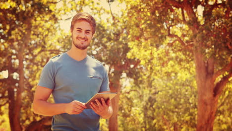 Hombre-Guapo-Usando-Tableta-Y-Mirando-A-La-Cámara-En-El-Parque