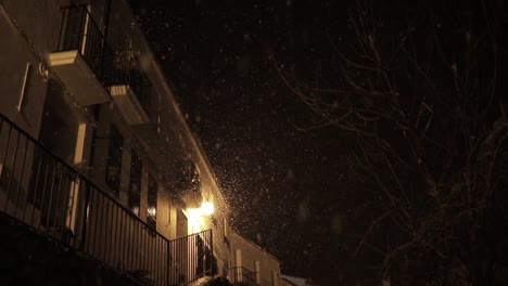 old building facades with shiny light in snowfall at night