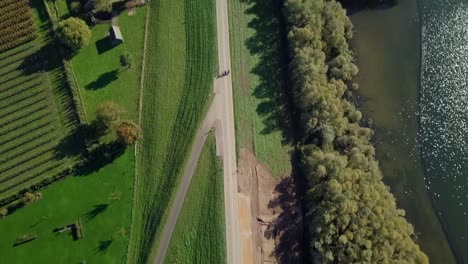 Aerial-drone-view-over-the-beautiful-road-revealing-the-beautiful-lake-and-greenhouses-in-the-Netherlands,-Europe