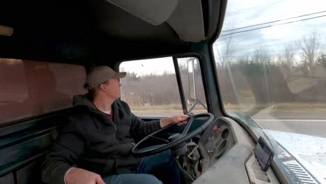 man driving vintage dump truck fast on highway, interior view