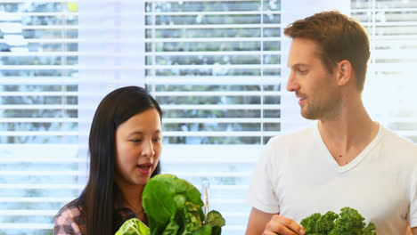 Pregnant-couple-holding-fresh-leafy-vegetable-in-kitchen-4k