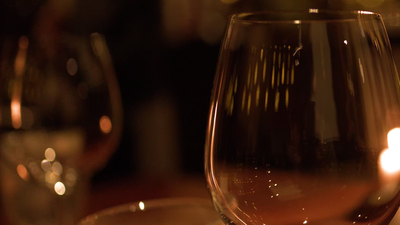 Primo piano di un calice di vino vuoto su un tavolo con una calda luce di candela e bokeh delicato