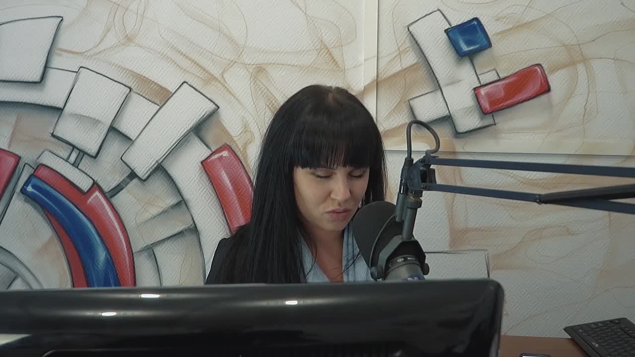 dj de radio en el estudio de transmisión la chica pone un dedo en la cabeza representando la fatiga