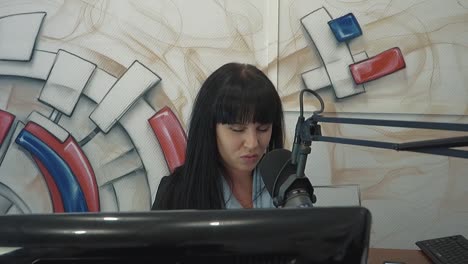 방송 스튜디오의 라디오 디제이 소녀는 피로를 나타내는 머리에 손가락을  ⁇ 습니다.