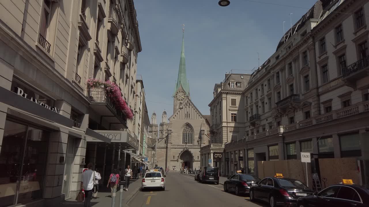 A view down a bustling city street towards the Fraumünster Church in Zurich, Switzerland