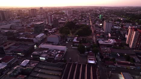 Dolly-in-aerial-view-of-a-blue-hour-with-purple-color,-with-traffic-on-the-streets,-cars-with-lights-flashing