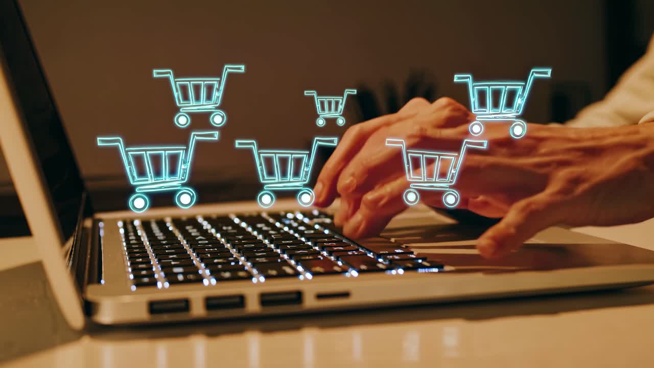 Close-up, side angle of hands typing on a laptop with glowing shopping cart icons