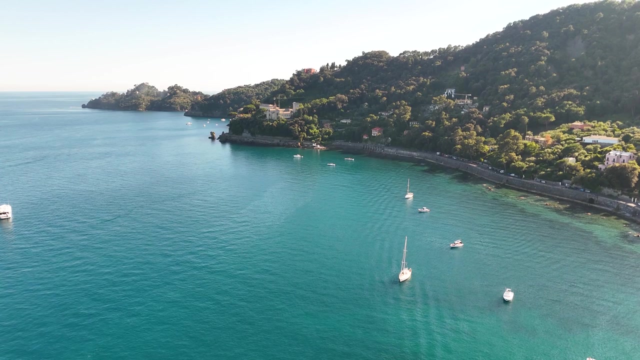 Ripresa aerea con drone che cattura barche di lusso che galleggiano su acqua turchese vicino a una costa lussureggiante