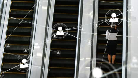 Animation-of-network-of-profile-icons-over-rear-view-of-businesswoman-on-escalator-at-modern-office