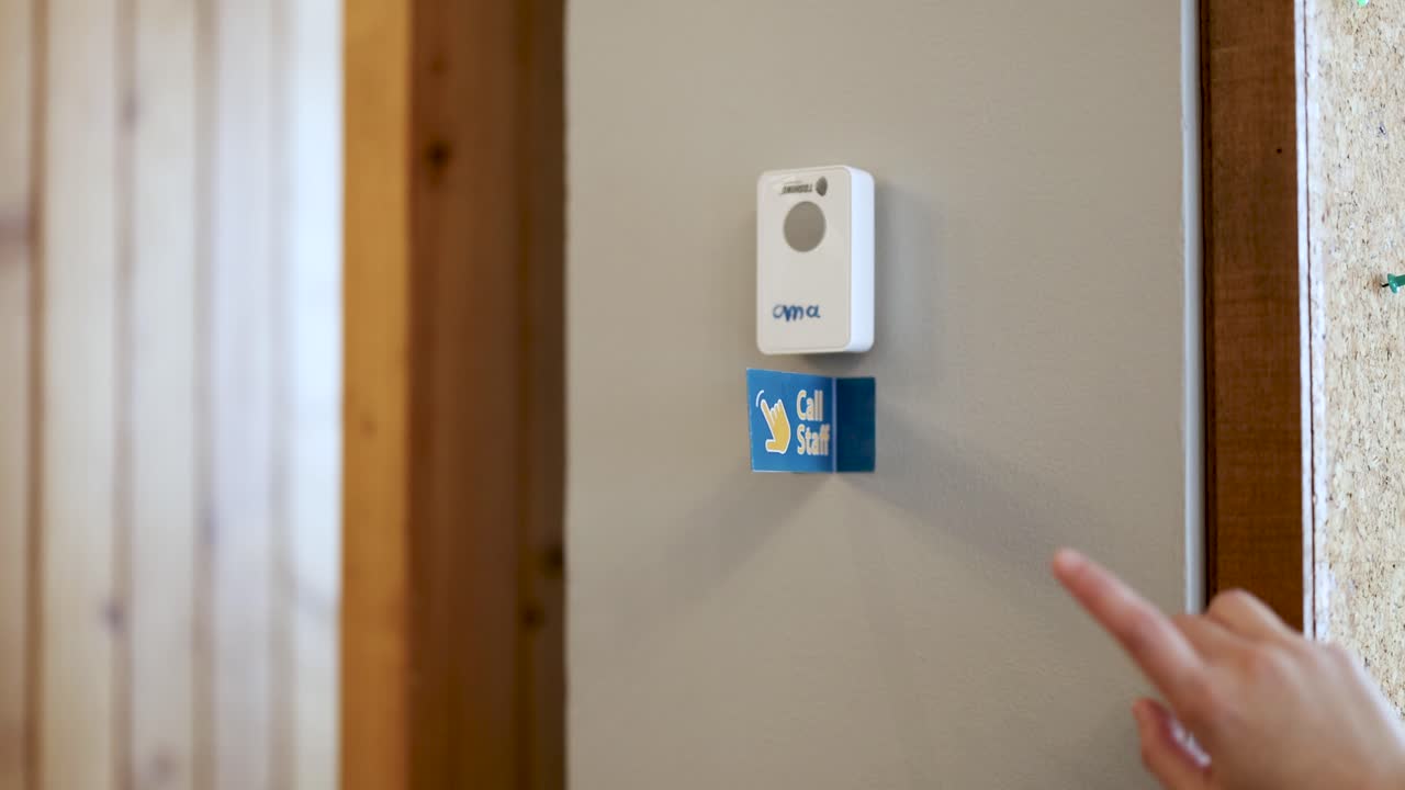 Hand presses wall-mounted call staff button in restaurant, natural daylight, static camera, close-up view