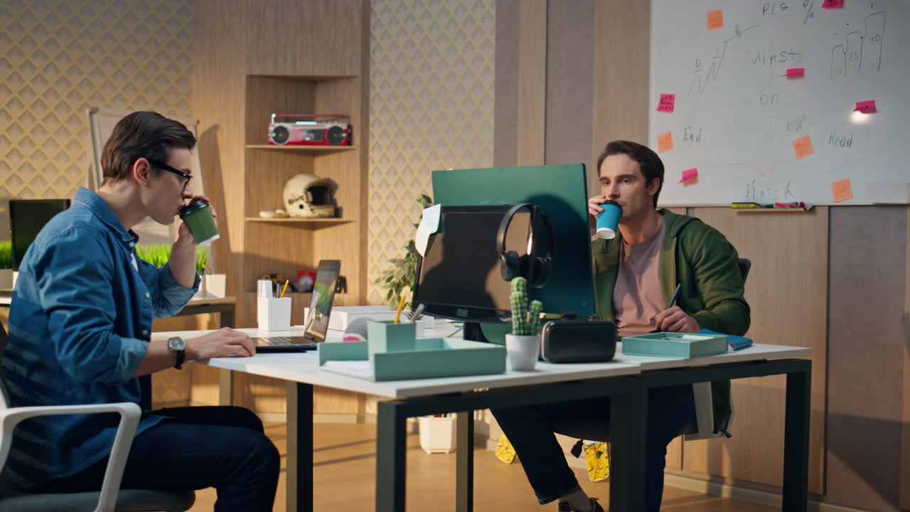 Inspired designers communicating together at office. Guys drinking tea working