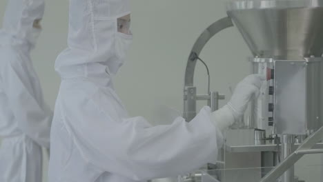 sterile pharmaceutical factory production line, workers in lab coats and masks are conducting quality control for medication vials, ensuring the safety and efficacy of the products being manufactured