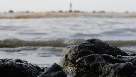 Low-shot-of-waves-crashing-into-the-rocky-beach