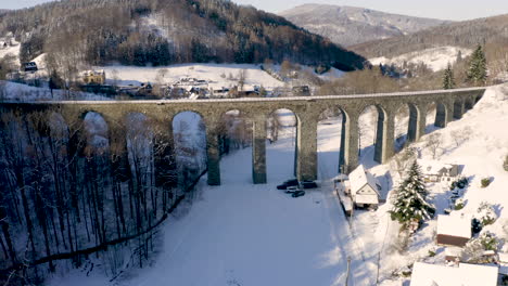 stone railway viaduct over a small czech village in winter snow,sunny