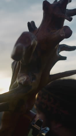 old igil with tree roots on neck and musician sitting in mountain valley at sunrise extreme closeup. ancient altai instrument and musical culture
