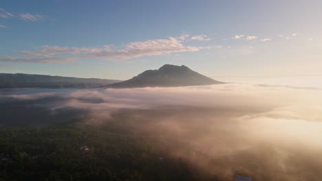 Toma-Aérea-De-Seguimiento-De-La-Espesa-Niebla-Matutina-Y-El-Pico-Del-Volcán-Butur-En-Bali.