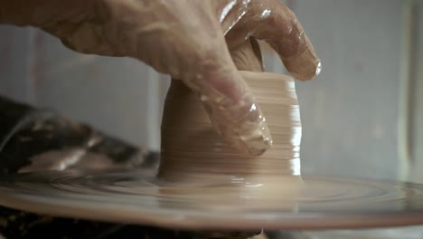 a potter teaches a woman to make clay dishes. a man takes a woman's hands