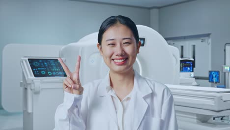close up of asian woman doctor showing gesture peace and smiling with mri machine in the hospital
