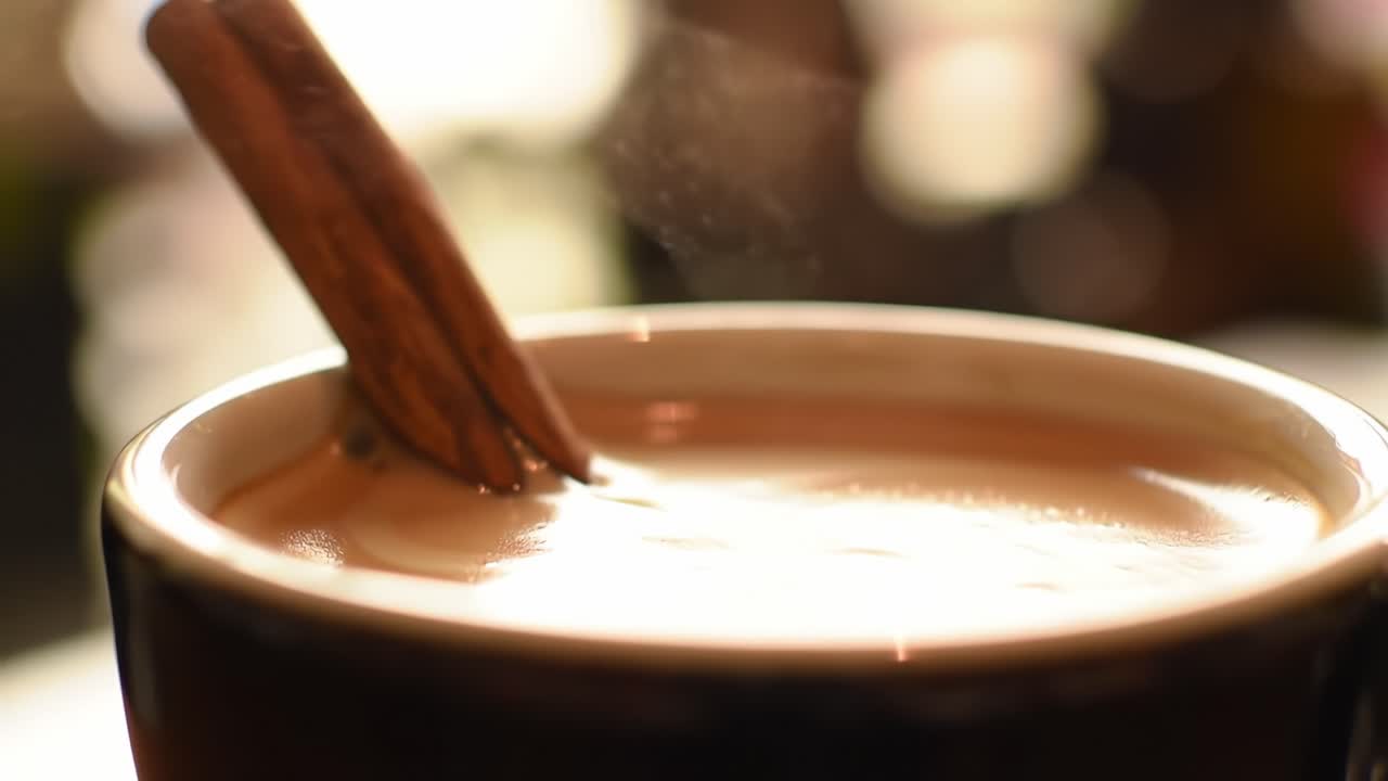 Infusing Flavor: A Close-Up View of Cinnamon Stirring in a Steaming Mug of Delicious, Creamy Beverage, Evoking Comfort and Warmth on a Cozy Day