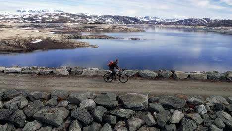 toma aérea de un hombre en bicicleta a través de la presa sysen en el municipio de eidfjord en hordaland, noruega