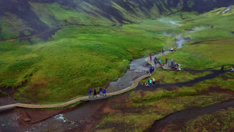 gente caminando por el sendero junto al río caliente en el valle de reykjadalur en islandia