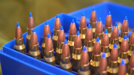 blue ammunition box full of 223 caliber military grade bullets with blue plastic tip for rapid expansion - slider from left to right