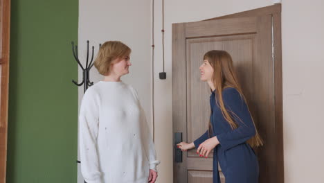 back view of psychologist opening wooden door with warm smile as patient sits on chair nearby excited for session in modern office with green white walls and black coat rack and bright aesthetic