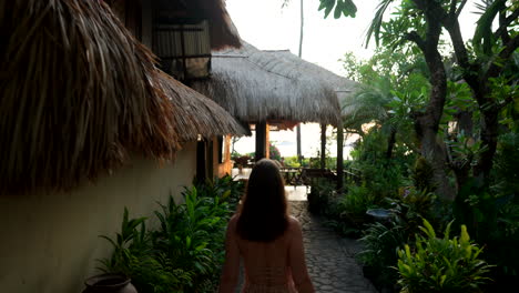 tourist woman walking towards the restaurant at the hotel accommodation during sunrise in bali, indonesia