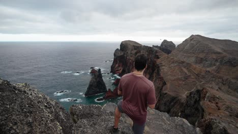 a man prepares to launch a drone while standing on a rocky cliff at ponta de são lourenço in madeira, portugal.