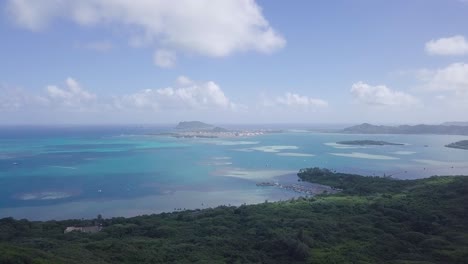 wide landscape vista of eest honolulu oahu hawaii and the clear blue pacific ocean waters and island in the background with white fluffy clouds, aerial dolly