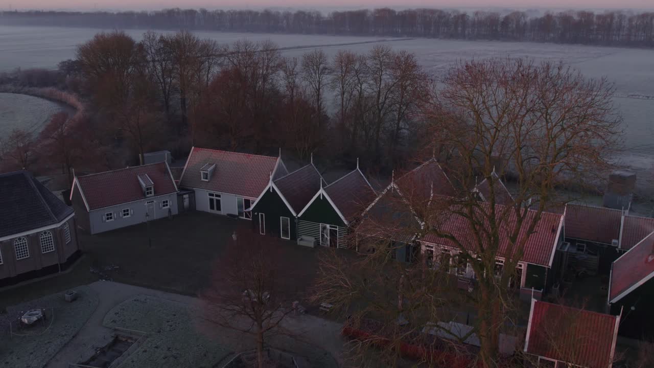 Aerial shot of serene village with church and trees in sunrise light, Schokland